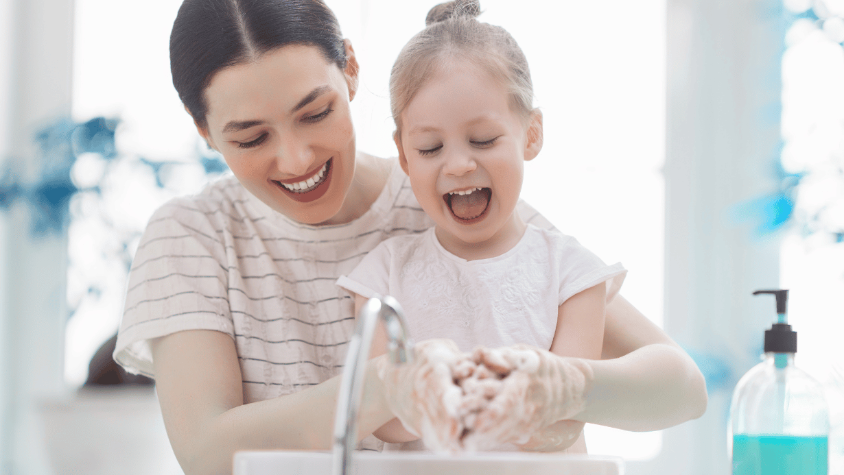 A mother teaches her daughter infection control through hand washing.
